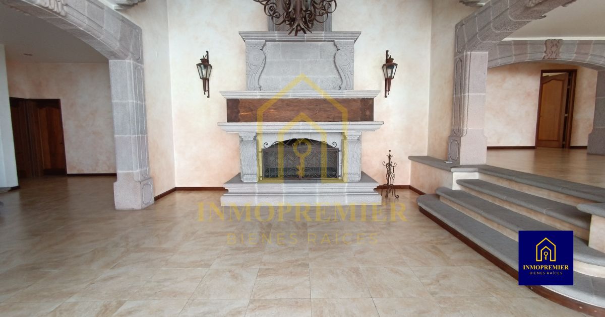 Sala principal con chimenea de cantera en casa en venta en Prados del Campestre Morelia dentro de residencia de lujo con espacios de convivencia de gran formato