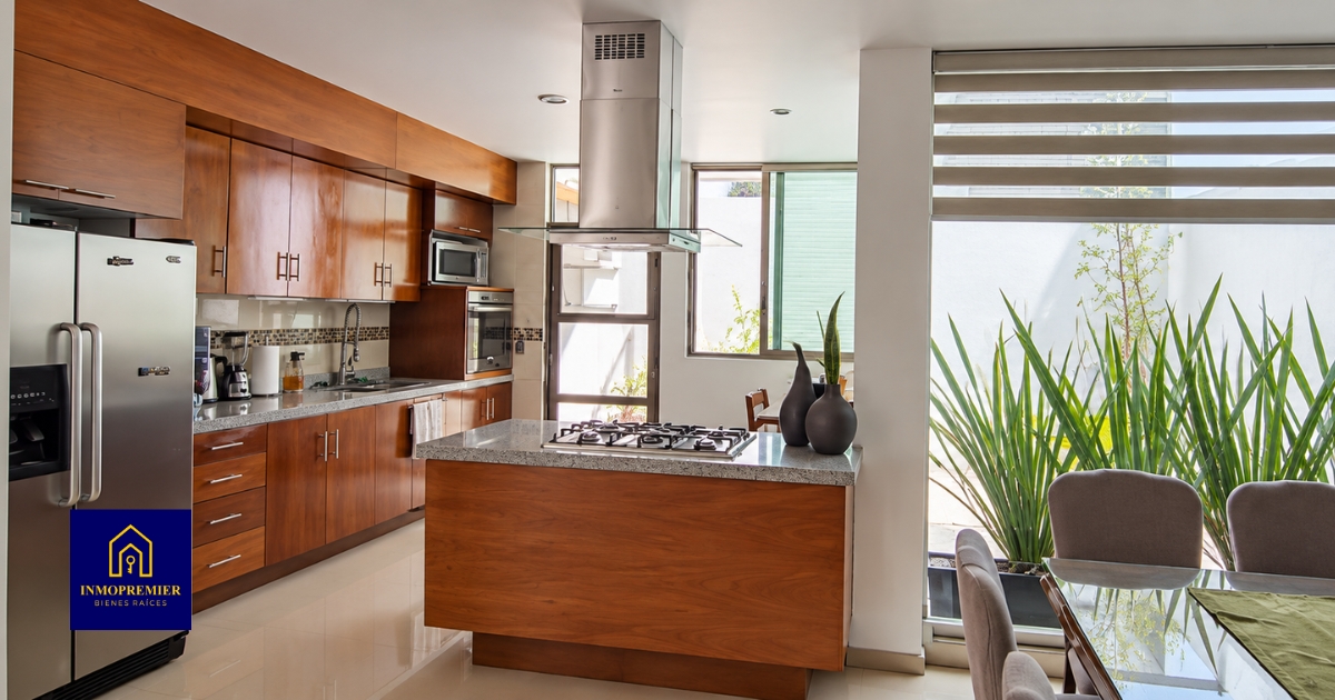 Cocina con isla y comedor junto a ventanal con vegetación